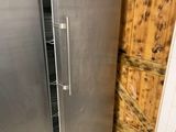 un réfrigérateur en acier inoxydable dans une cuisine dont l'un des murs est en bois