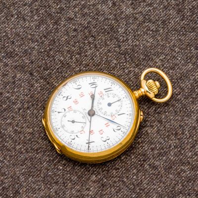 un gros plan d'une montre de poche posée sur une surface marron