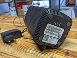 a black fan on a wooden table with a small charger