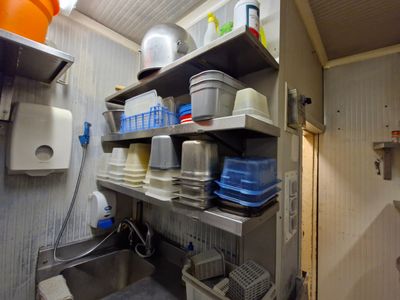 une petite cuisine avec un évier et des étagères remplies de vaisselle