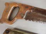 a wooden hand saw and a metal hand saw on a table