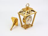 a small gold clock with a bird on top of it