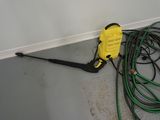 a yellow pressurer sitting on the floor next to some green hoses