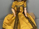 une ravissante jeune femme en robe jaune, assise sur un bloc de bois