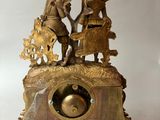 a gold clock with a picture of a man and a woman on it