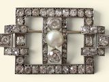 une image représentant une broche ornée de perles et de diamants sur fond blanc