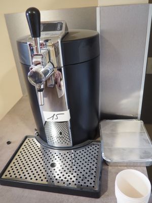 une machine à café posée sur un plan de travail, à côté d'une tasse