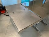 a stainless steel table with a glass top in a room