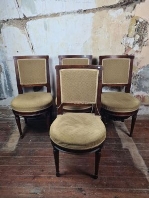 four chairs with upholstered seats in a room with a wall in the background