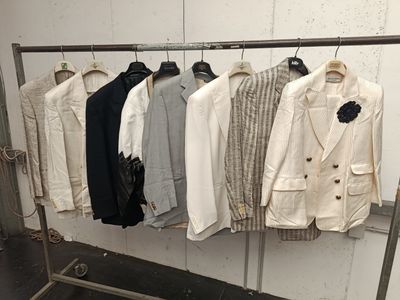 a lot of jackets hanging on a rack in a room