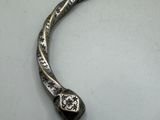 a silver bracelet with a flower on it on a table
