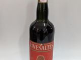 une vieille bouteille de vin posée sur une table blanche