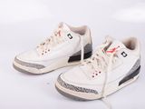 une paire de baskets blanches avec des touches de noir et de rouge sur fond blanc