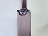 une bouteille en verre violette avec un bouchon orange posée sur une table en bois