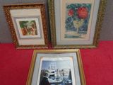trois photos encadrées représentant des bateaux et des fleurs, posées sur une table rouge