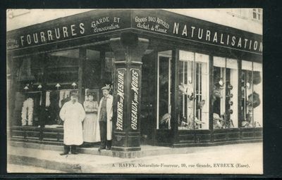 une vieille photo en noir et blanc montrant deux hommes et une femme debout devant un magasin