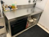 un plan de travail en acier inoxydable dans une cuisine dont le sol est recouvert d'un tapis noir