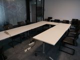 des tables et des chaises dans une salle de conférence, avec un mur vitré en arrière-plan