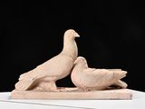 pair of birds sitting on a white pedestal against a black background