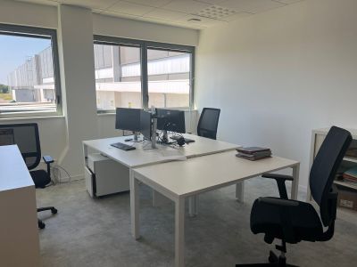 un bureau blanc sur lequel sont posés deux ordinateurs, dans un bureau