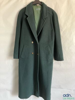a green coat is hanging on a hanger on a wall