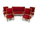 four red velvet chairs and a sofa with gold trim