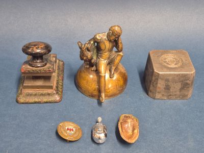 une petite statue représentant un homme assis sur un tabouret, à côté d'autres objets