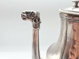 a silver tea pot with a dragon head on it