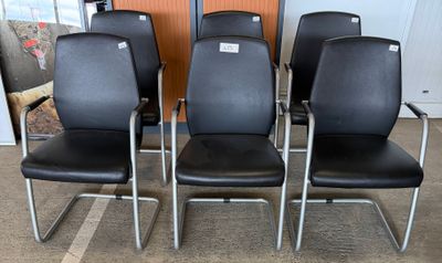 four black leather chairs with chrome legs in a room
