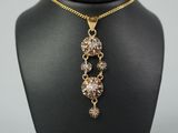 une image représentant un collier composé d'une chaîne en or et d'un pendentif en cristal
