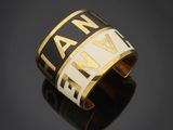 a close up of a black and gold cuff bracelet with a name on it