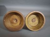 two wooden bowls are sitting on a table with a gray background
