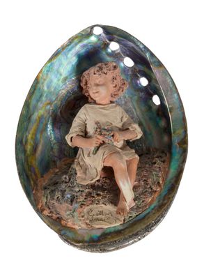 une figurine représentant un garçon assis dans un coquillage