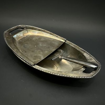 une assiette en argent sur laquelle repose une cuillère, posée sur un fond noir