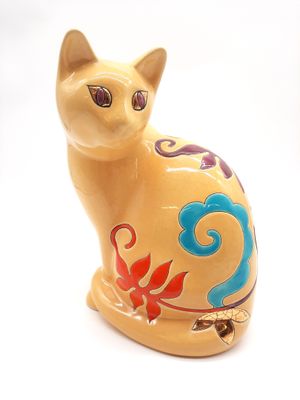 une figurine de chat jaune posée sur une surface blanche