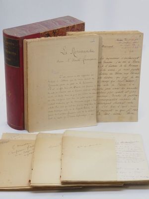un livre ouvert posé sur une table blanche, à côté d'un livre rouge