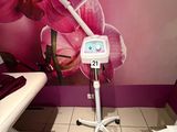 a room with a chair, a table, and a wall with a picture of a pink orchid