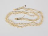 a close up of a white pearl necklace with a gold clasp