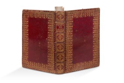 un vieux livre à la couverture rouge posé sur une surface blanche