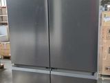 a silver refrigerator in a warehouse with pallets on the floor