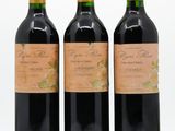 trois bouteilles de vin posées les unes à côté des autres sur une surface blanche