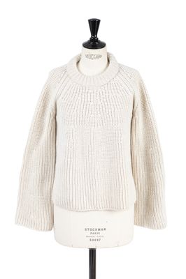 un pull blanc posé sur un mannequin, devant un fond blanc