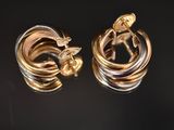 deux boucles d'oreilles en forme d'anneaux, l'une en or et l'autre en argent, sur un fond noir