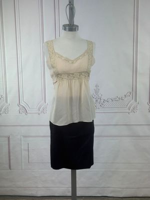beige and black dress on a mannequin stand in front of a white wall
