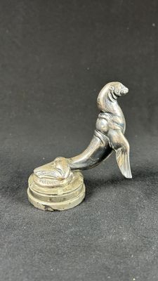an old silver figurine of a dog sitting on top of a bowl