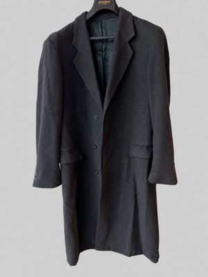 a black coat hanging on a hanger on a white wall