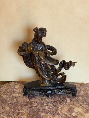 bronze figurine of a woman sitting on a marble table