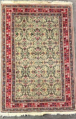 an antique persian rug with a floral design on a green ground