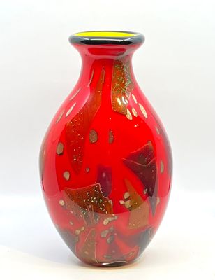 un vase rouge surmonté d'un couvercle jaune, posé sur une surface blanche