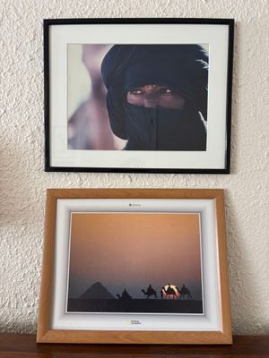 framed photograph of a woman in a black veil and a camel in the desert
